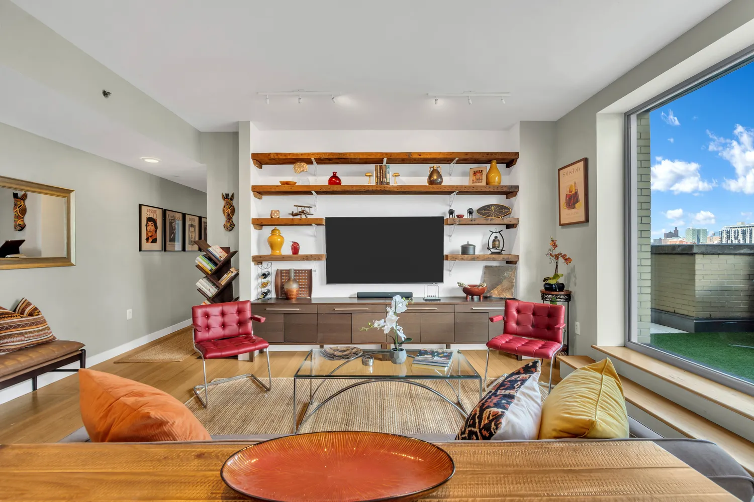 a living room with furniture a flat screen tv and a floor to ceiling window