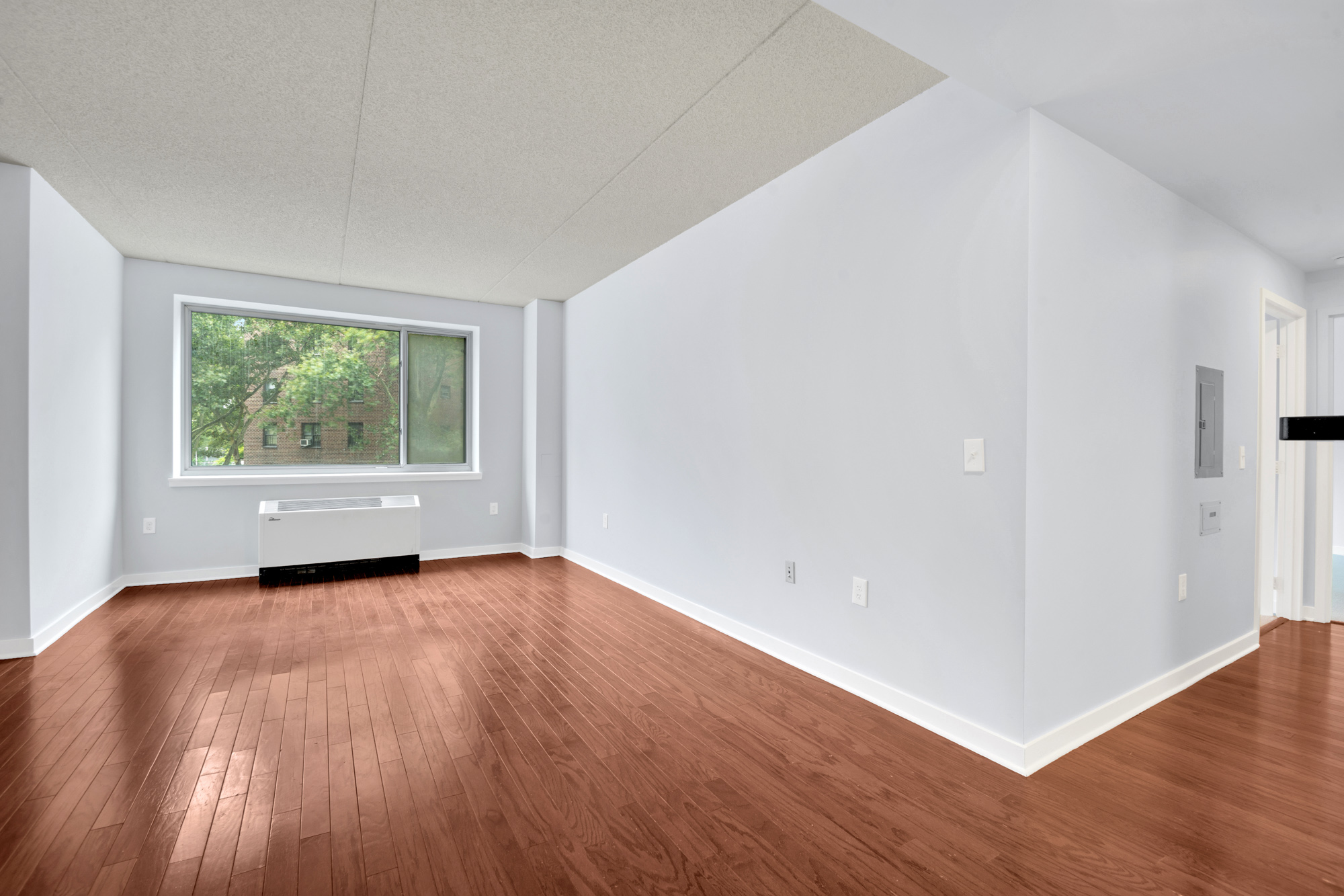 40 West 116th Street, Unit B205 Manhattan, NY 10026 - Photo 2 of 24 a view of an empty room with wooden floor and a window