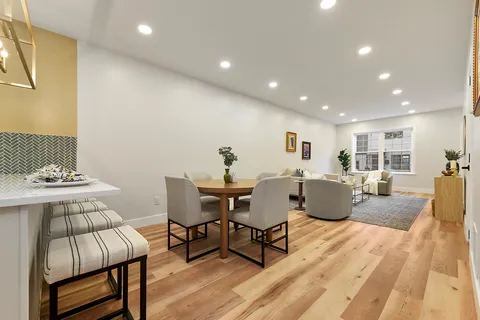a kitchen with granite countertop a refrigerator sink stove and white cabinets