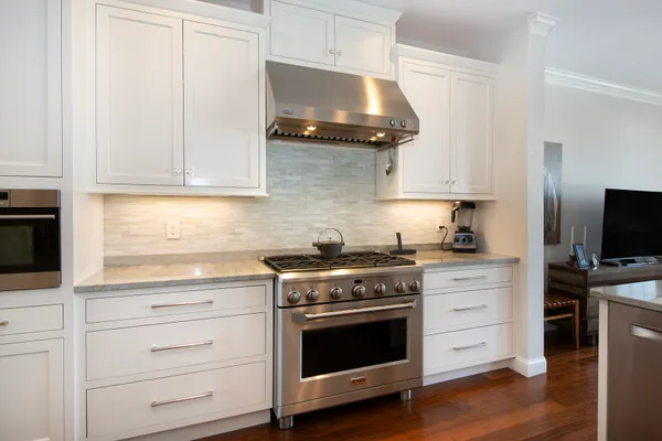 a kitchen with stainless steel appliances granite countertop a refrigerator a stove a sink dishwasher and a dining table with wooden floor