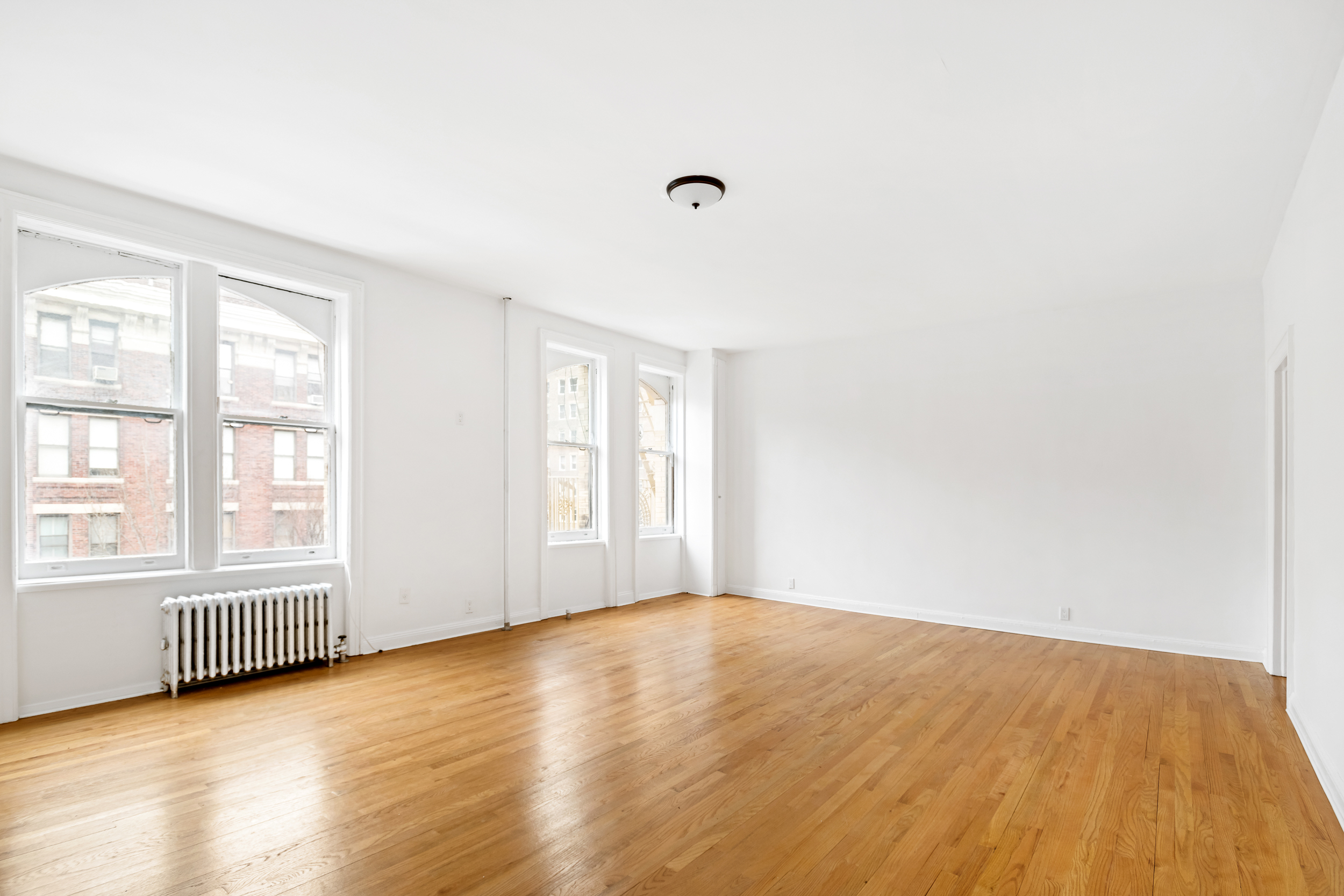 50 East 96th Street, Unit 5D Manhattan, NY 10128 - Photo 1 of 5 an empty room with wooden floor and windows