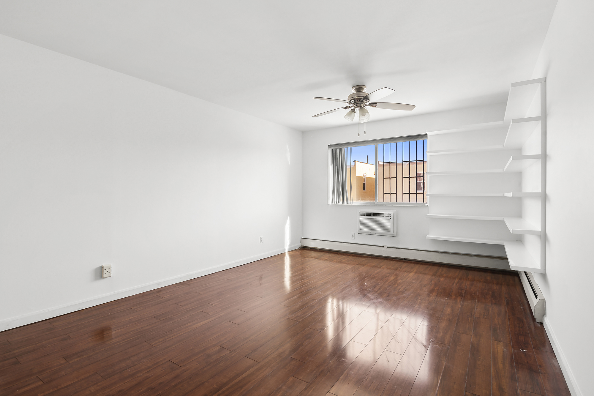 21-08 Butler Avenue, Unit J2 Queens, NY 11385 - Photo 8 of 14 wooden floor in an empty room with a window