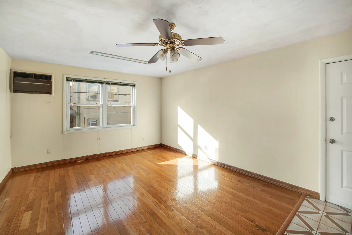 a view of an empty room with wooden floor and a window