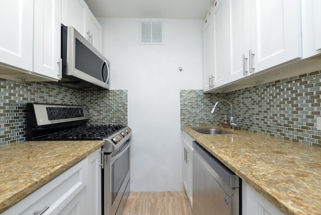 102-10 66th Road, Unit 21K Queens, NY 11375 - Photo 6 of 16 a kitchen with granite countertop a sink a stove and cabinets