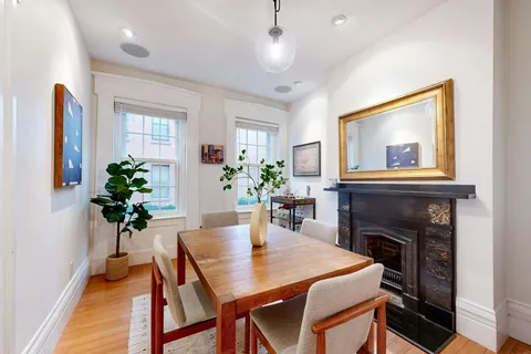a dining room with furniture potted plants and wooden floor