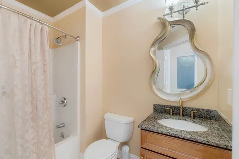 a bathroom with a granite countertop sink toilet and a mirror
