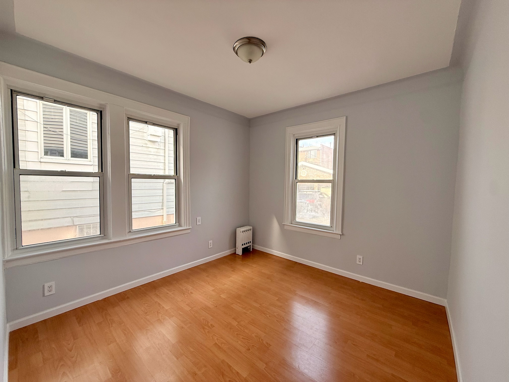 1675 85th Street, Unit 1R Brooklyn, NY 11214 - Photo 3 of 8 a view of an empty room with wooden floor and a window