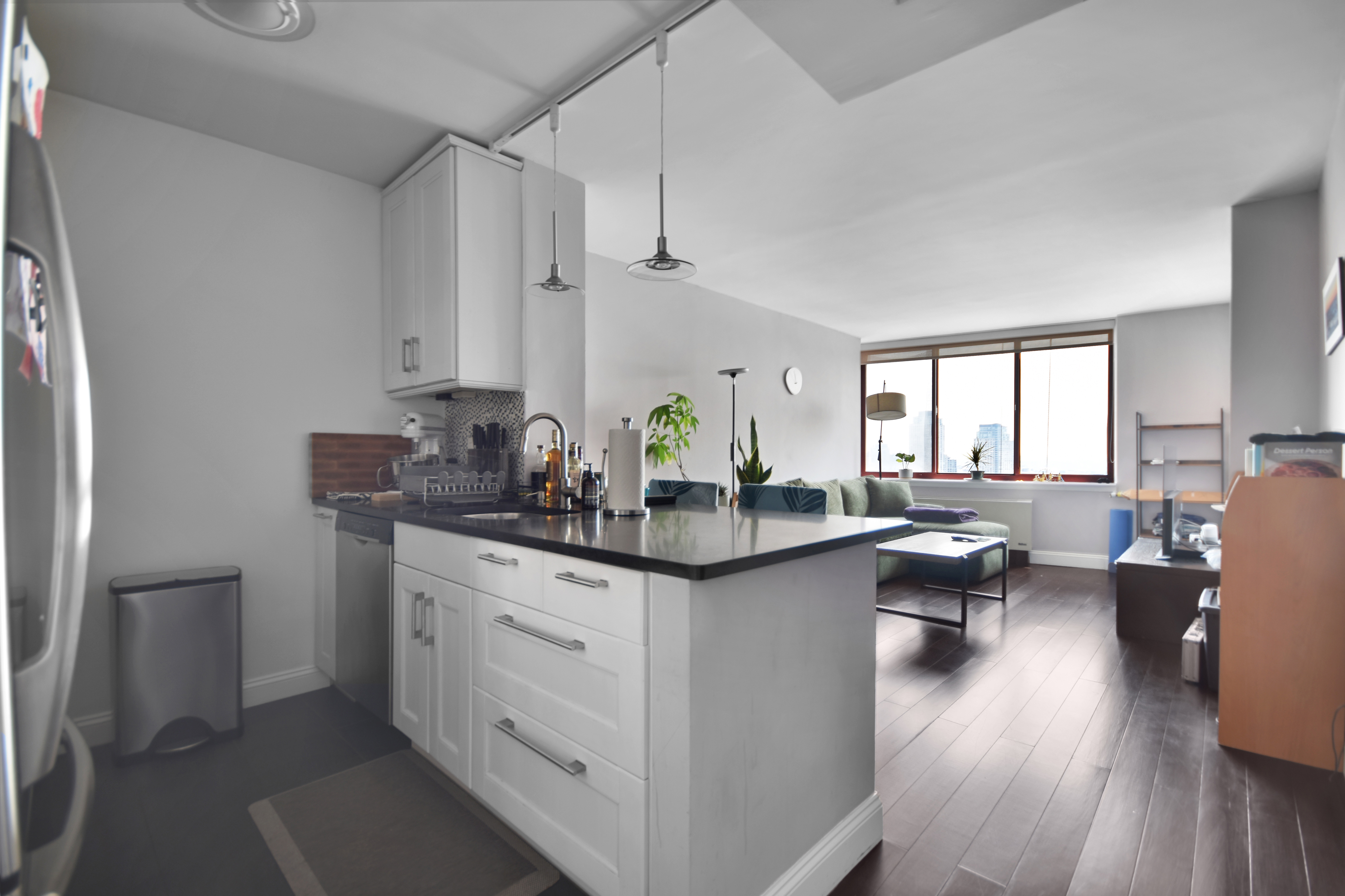 4-74 48th Avenue, Unit 34G Queens, NY 11109 - Photo 4 of 9 a kitchen with stainless steel appliances granite countertop sink cabinets and wooden floor