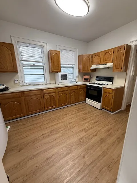 a view of kitchen with stainless steel appliances wooden floor and a refrigerator