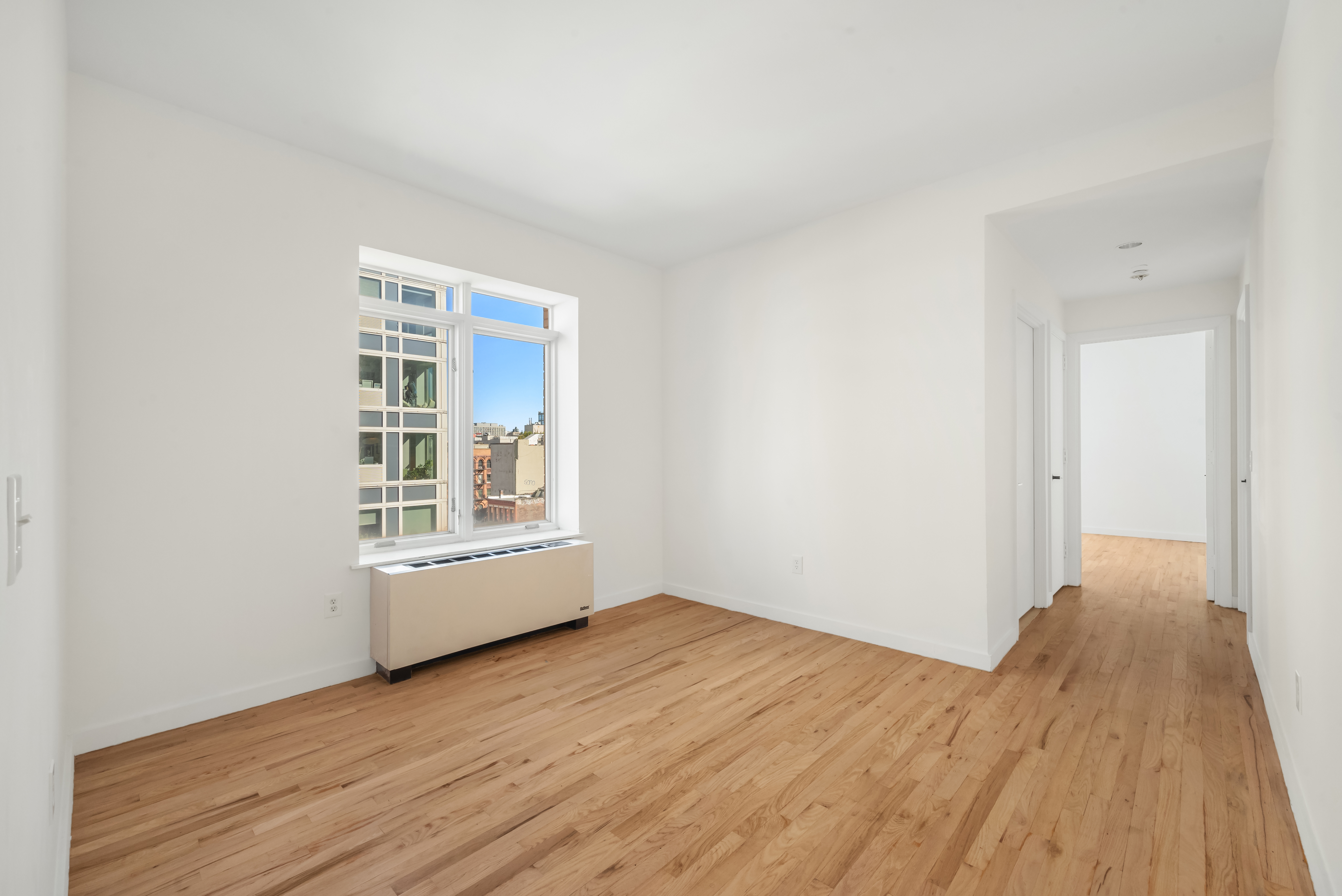 304 West 115th Street, Unit 6A Manhattan, NY 10026 - Photo 4 of 14 a view of an empty room with wooden floor and a window