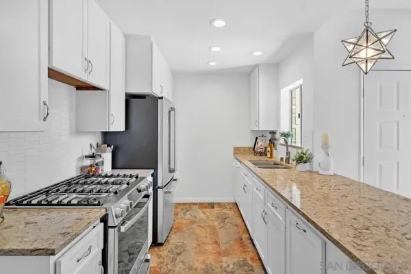 a kitchen with granite countertop a sink stove and refrigerator