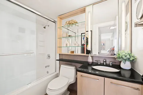a bathroom with a granite countertop sink toilet a large mirror a shower and a bathtub