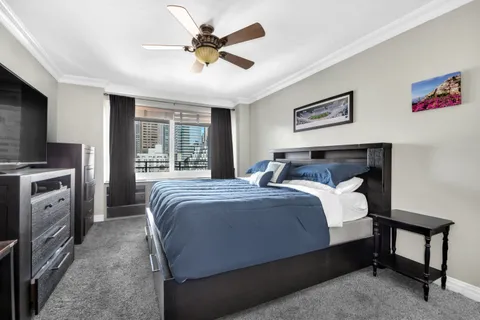 a bedroom with a bed a chandelier and a flat tv screen