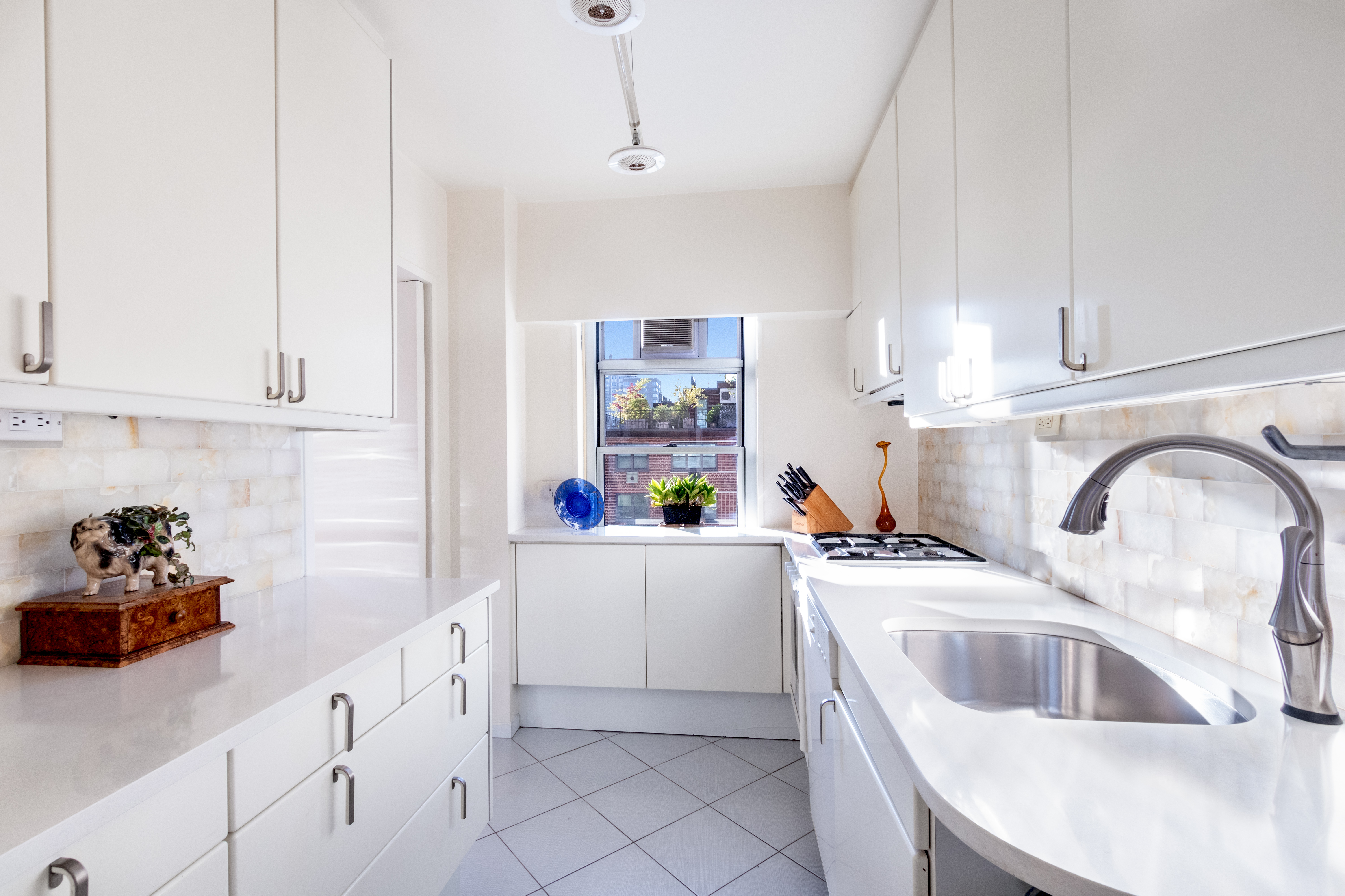 70 East 10th Street, Unit 14M Manhattan, NY 10003 - Photo 5 of 22 a kitchen with white cabinets a sink dishwasher and a stove with wooden floor