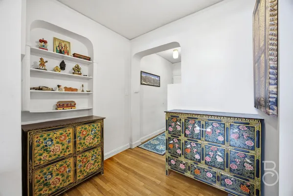 a view of a hallway with wooden floor and a book shelf