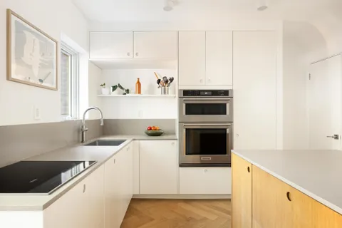 a kitchen with granite countertop a sink and white cabinets with stainless steel appliances