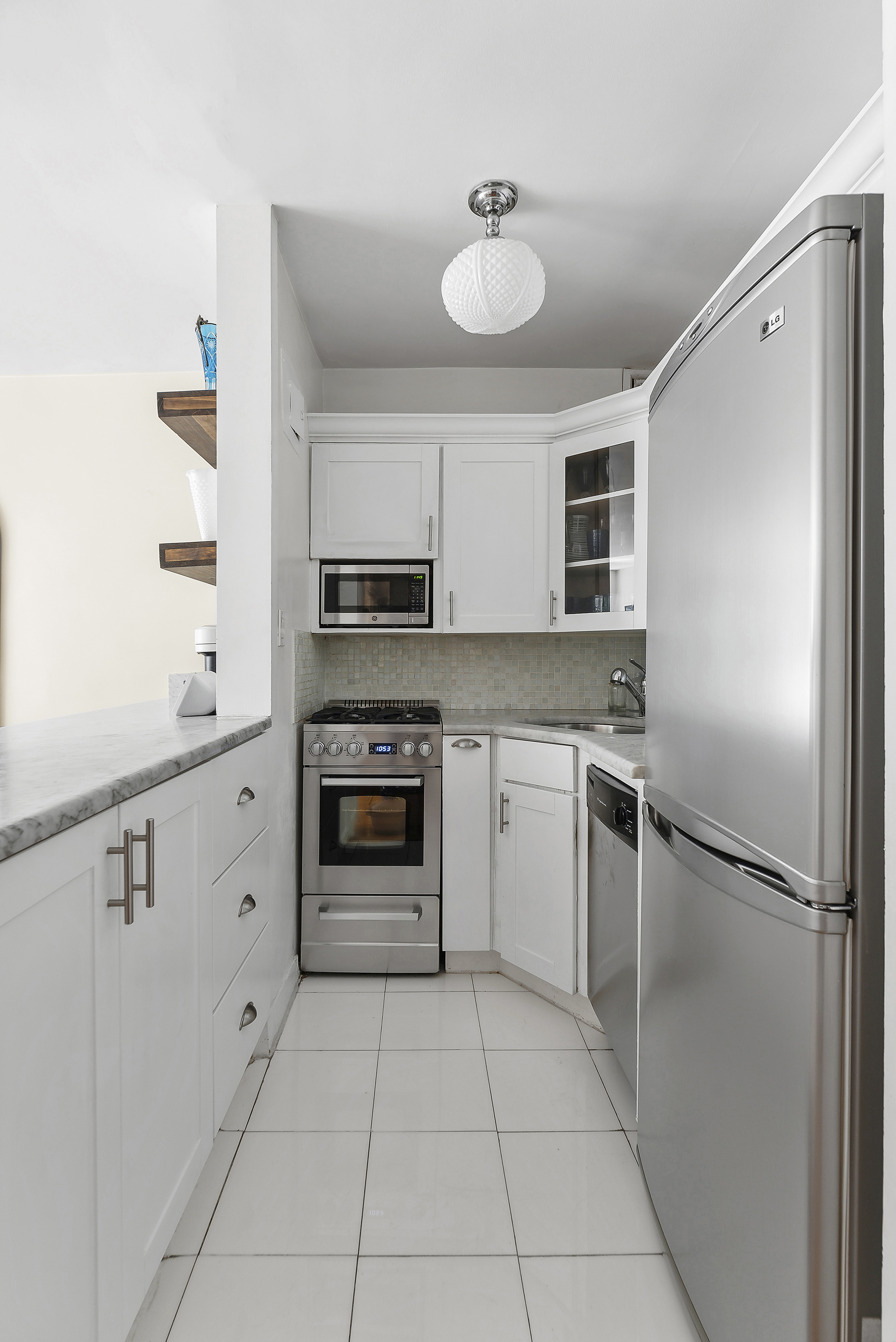 245 East 24th Street, Unit 10D Manhattan, NY 10010 - Photo 3 of 6 a kitchen with a refrigerator sink and cabinets