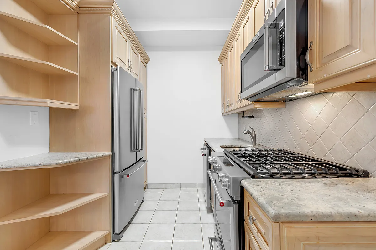 200 East 58th Street, Unit 15B Manhattan, NY 10022 - Photo 6 of 10 a kitchen with stainless steel appliances granite countertop a stove and a refrigerator
