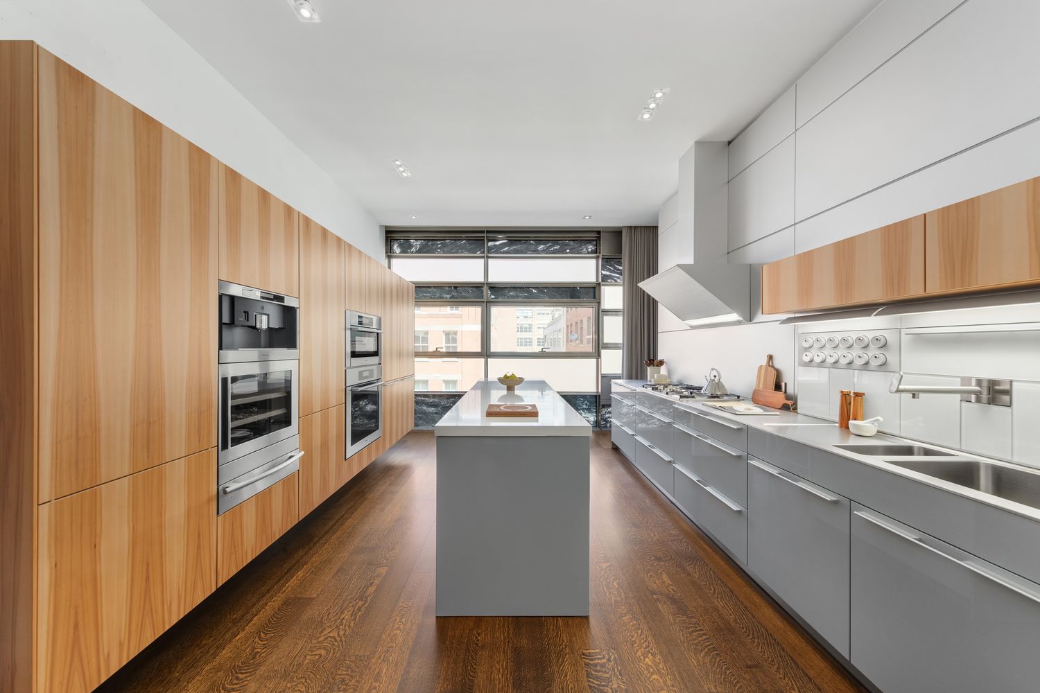 a kitchen with stainless steel appliances a refrigerator a sink dishwasher a stove and white countertops with wooden floor