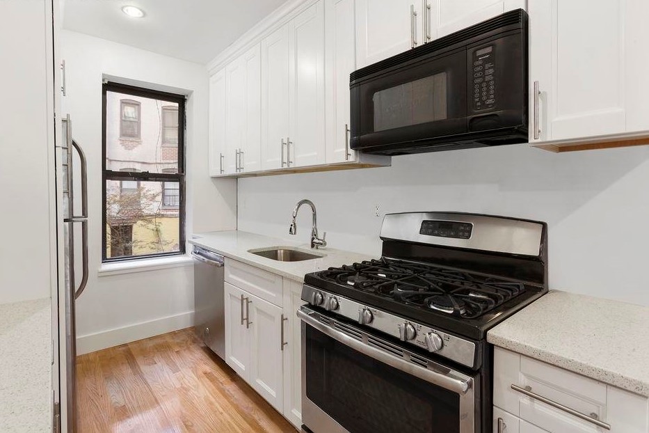 2116 Dorchester Road, Unit 1I Brooklyn, NY 11226 - Photo 4 of 15 a kitchen with stainless steel appliances a stove a microwave sink and cabinets