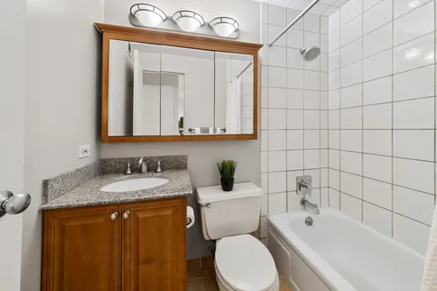 a bathroom with a granite countertop toilet sink and mirror