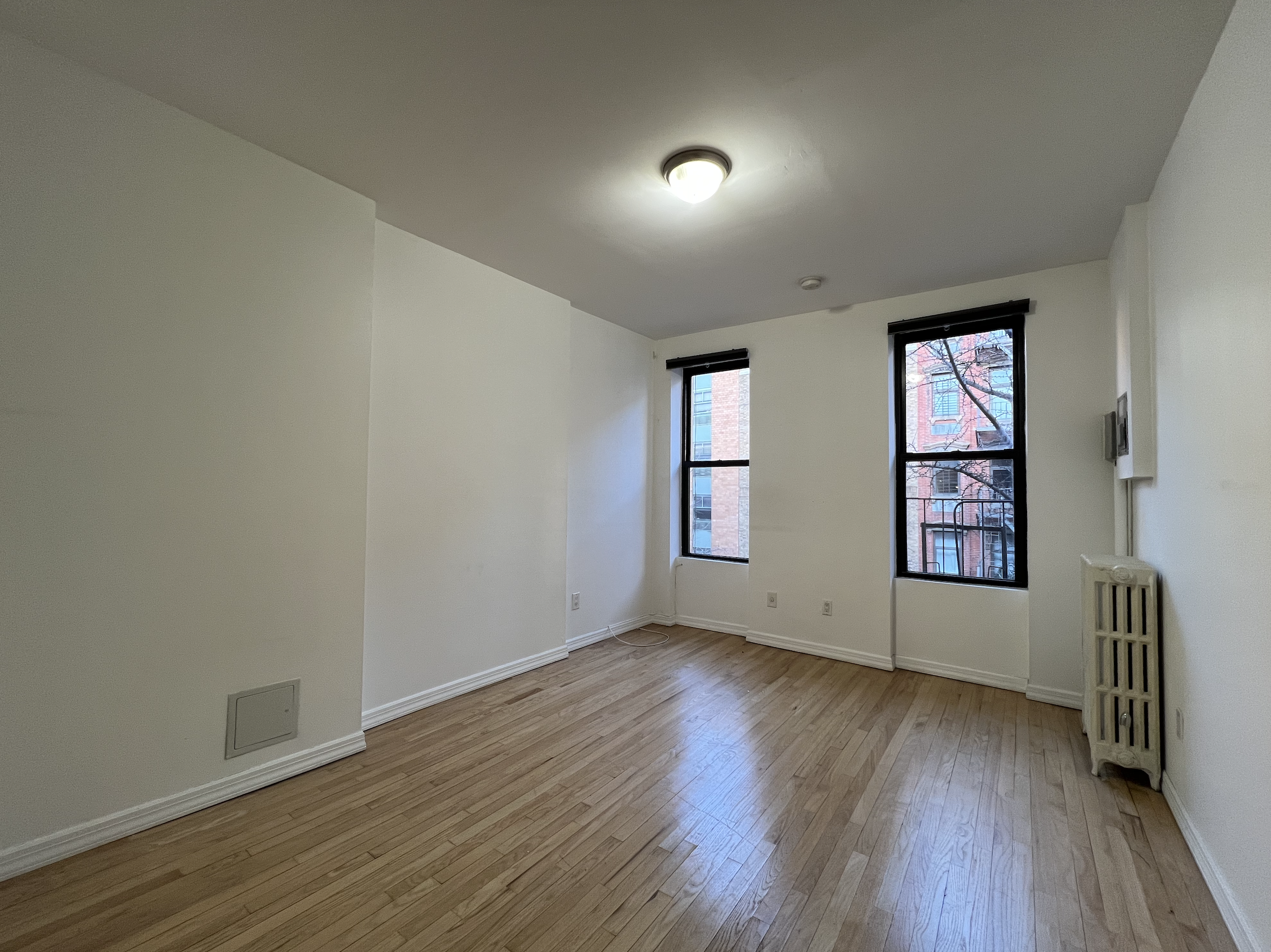 446 West 46th Street, Unit 5 Manhattan, NY 10036 - Photo 1 of 15 an empty room with wooden floor and windows