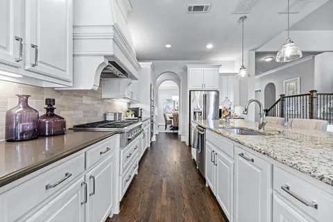 a large kitchen with stainless steel appliances granite countertop a lot of counter space and wooden floor