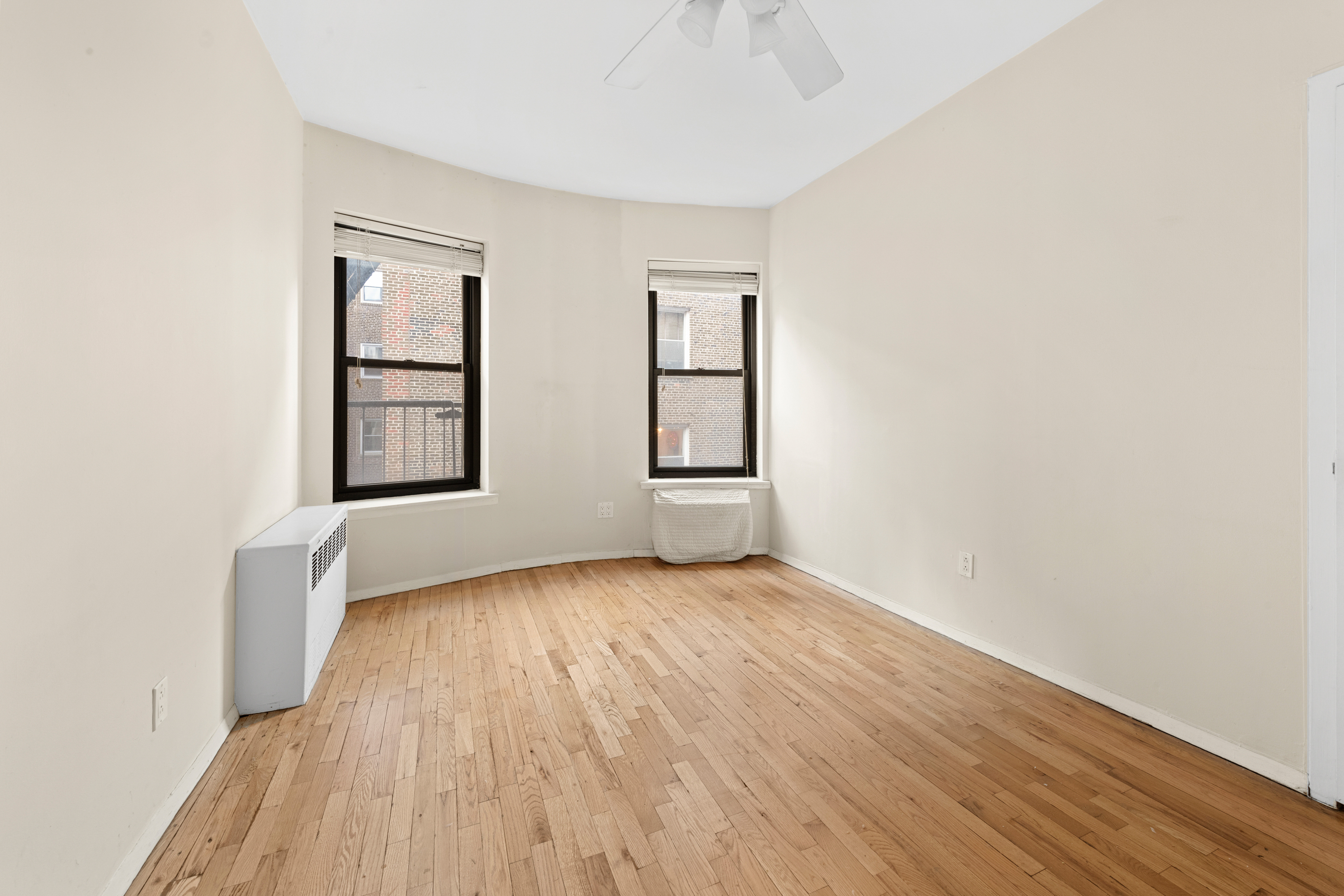 160 East 91st Street, Unit 4A Manhattan, NY 10128 - Photo 5 of 8 an empty room with wooden floor and windows