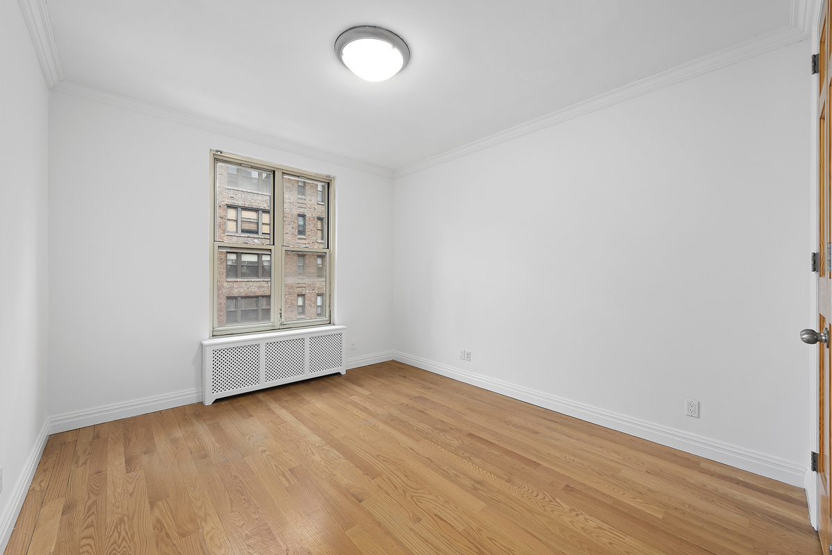 330 East 58th Street, Unit 4A Manhattan, NY 10022 - Photo 6 of 11 an empty room with wooden floor and windows