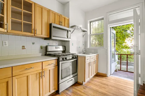 a kitchen with stainless steel appliances granite countertop a stove a sink and white cabinets with wooden floors