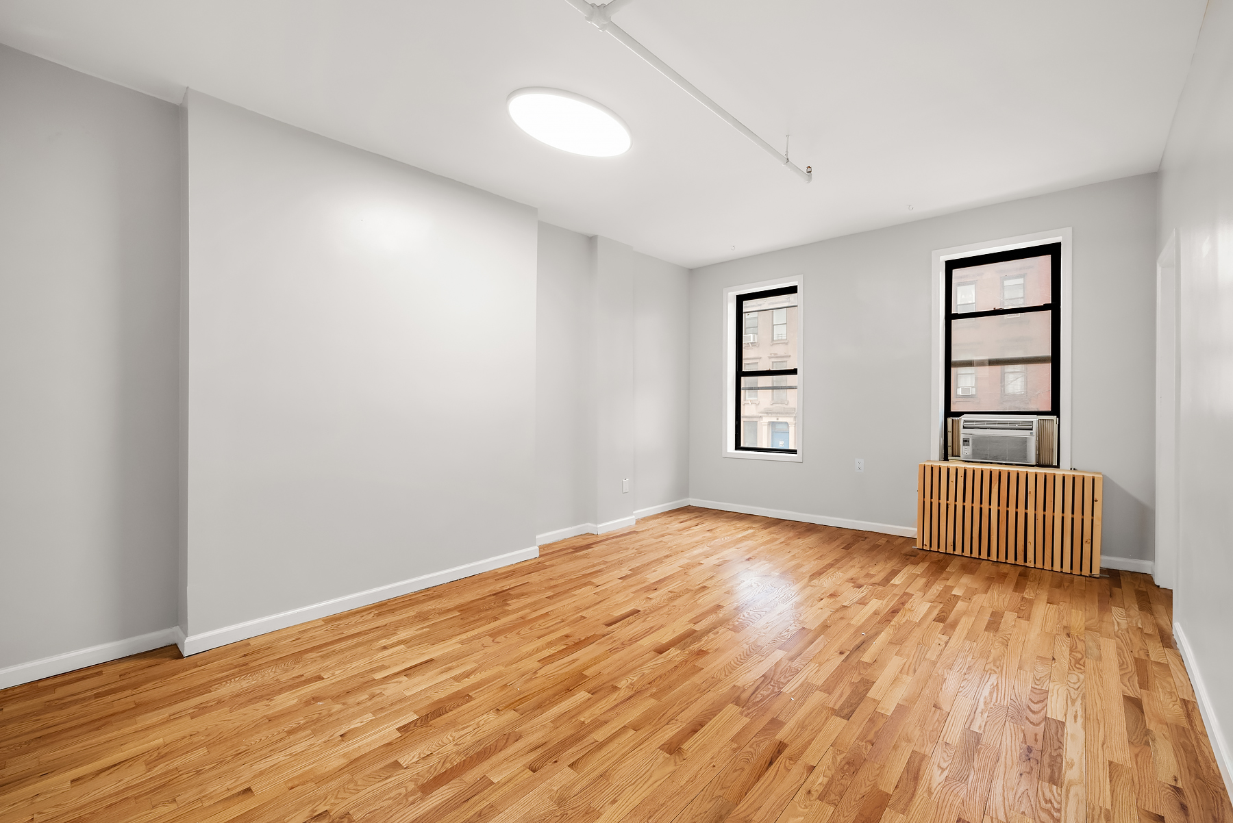 63 East 129th Street, Unit 3 Manhattan, NY 10037 - Photo 4 of 5 a view of empty room with wooden floor and fan
