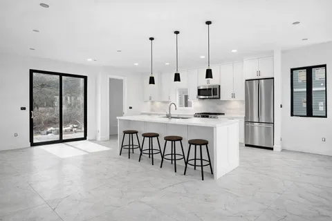 a large kitchen with stainless steel appliances kitchen island granite countertop a stove a sink a refrigerator and a dining table with wooden floor