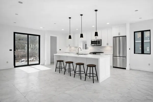 a large kitchen with stainless steel appliances kitchen island granite countertop a stove a sink a refrigerator and a dining table with wooden floor