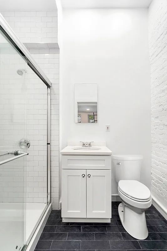 147 Sullivan Street, Unit 1A Manhattan, NY 10012 - Photo 5 of 6 a bathroom with a toilet a sink and shower
