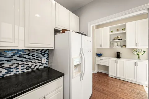 a kitchen with a refrigerator and white cabinets