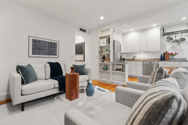 a living room with furniture kitchen view and a large window