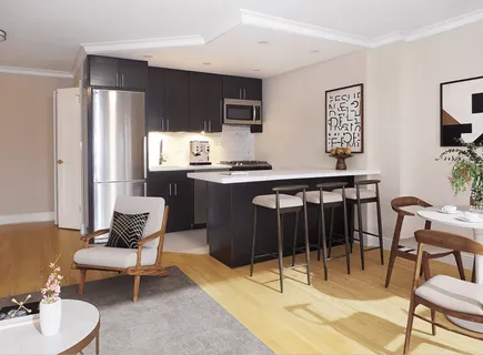 a living room with stainless steel appliances furniture a rug and a kitchen view