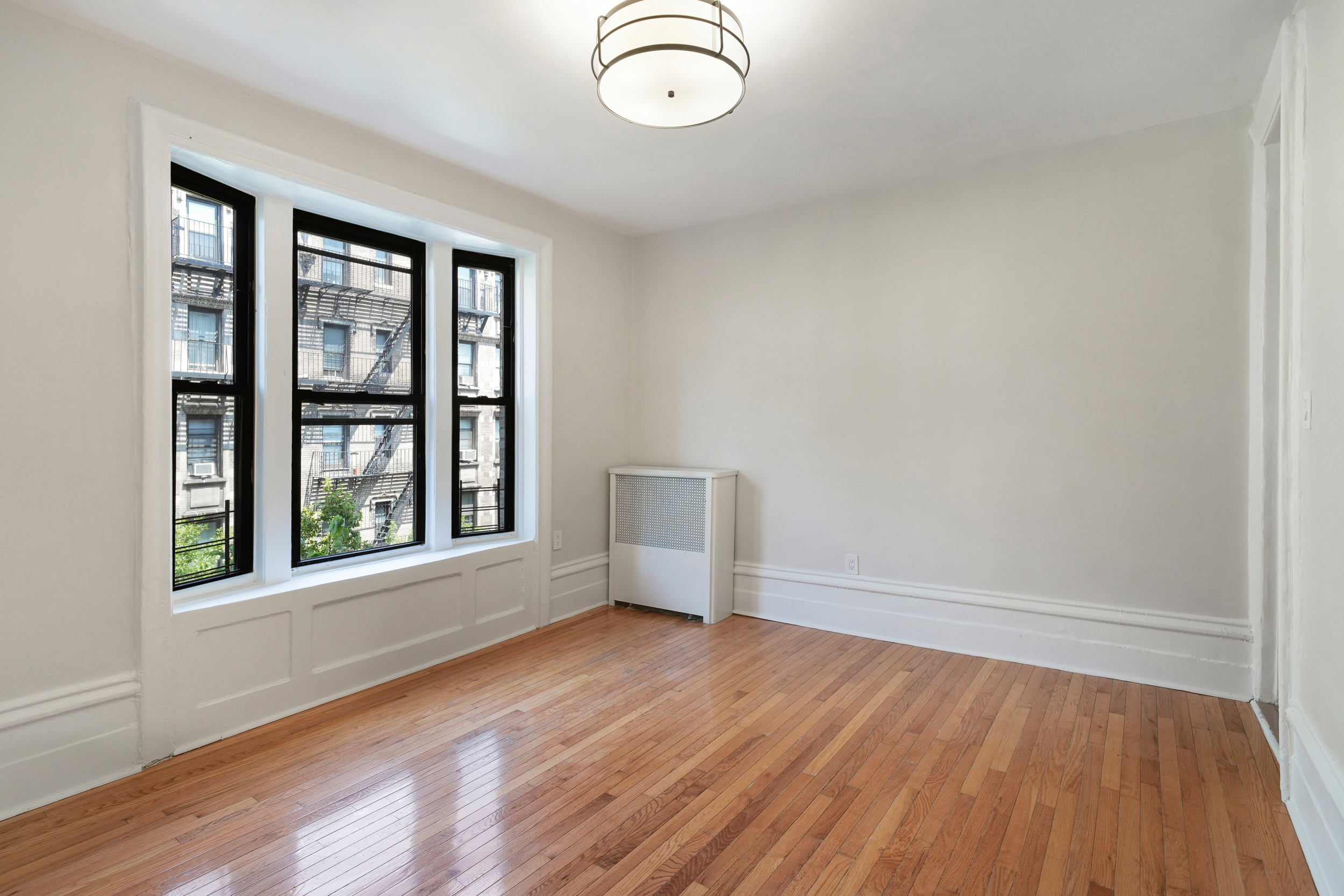 200 West 109th Street, Unit C1 Manhattan, NY 10025 - Photo 8 of 16 an empty room with wooden floor and windows