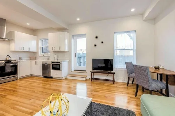 a living room with furniture wooden floor and a kitchen view