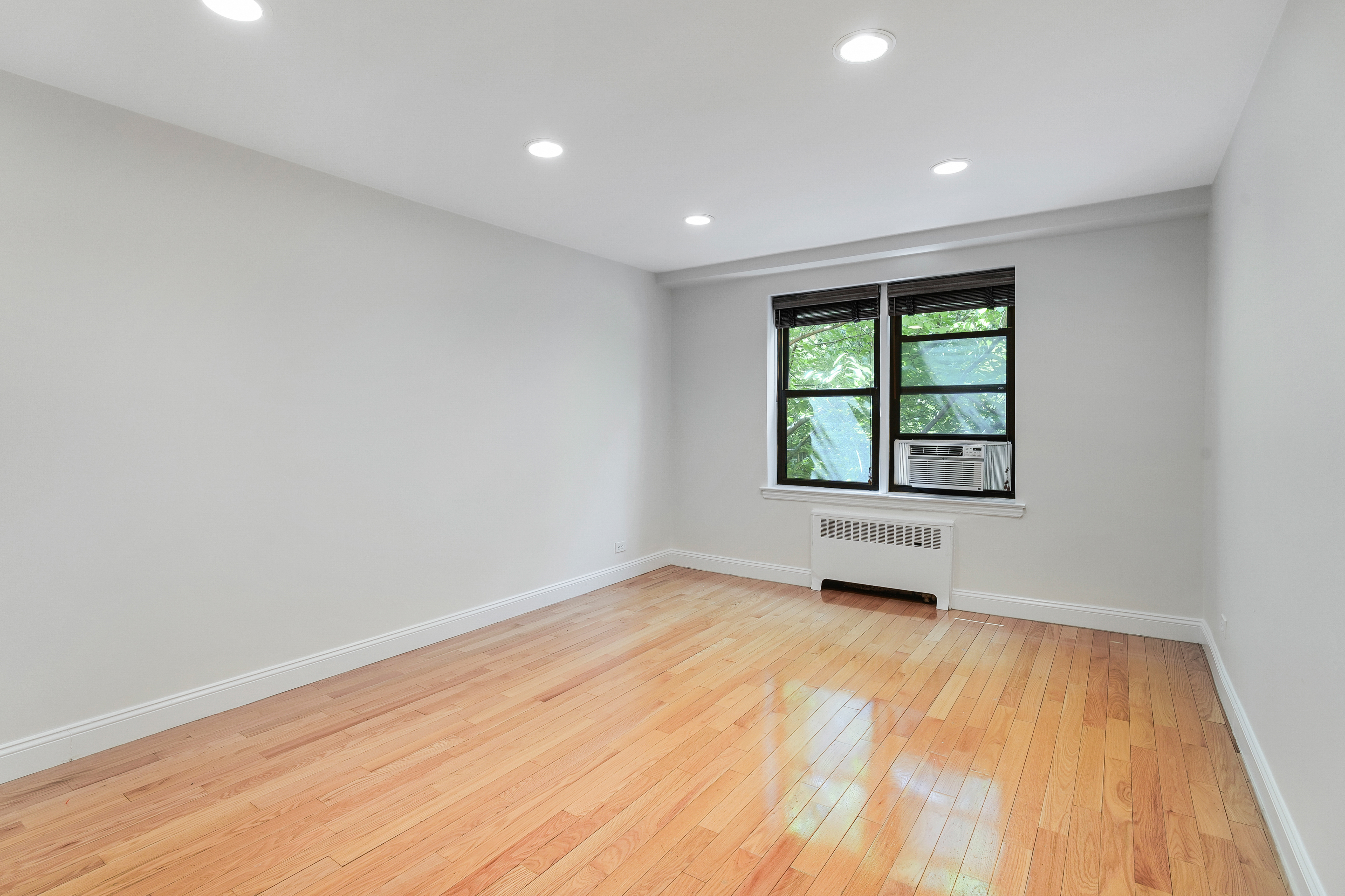 3840 Greystone Avenue, Unit 1K Bronx, NY 10463 - Photo 4 of 13 an empty room with wooden floor and windows