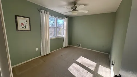 an empty room with windows and fan