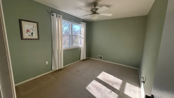 an empty room with windows and fan