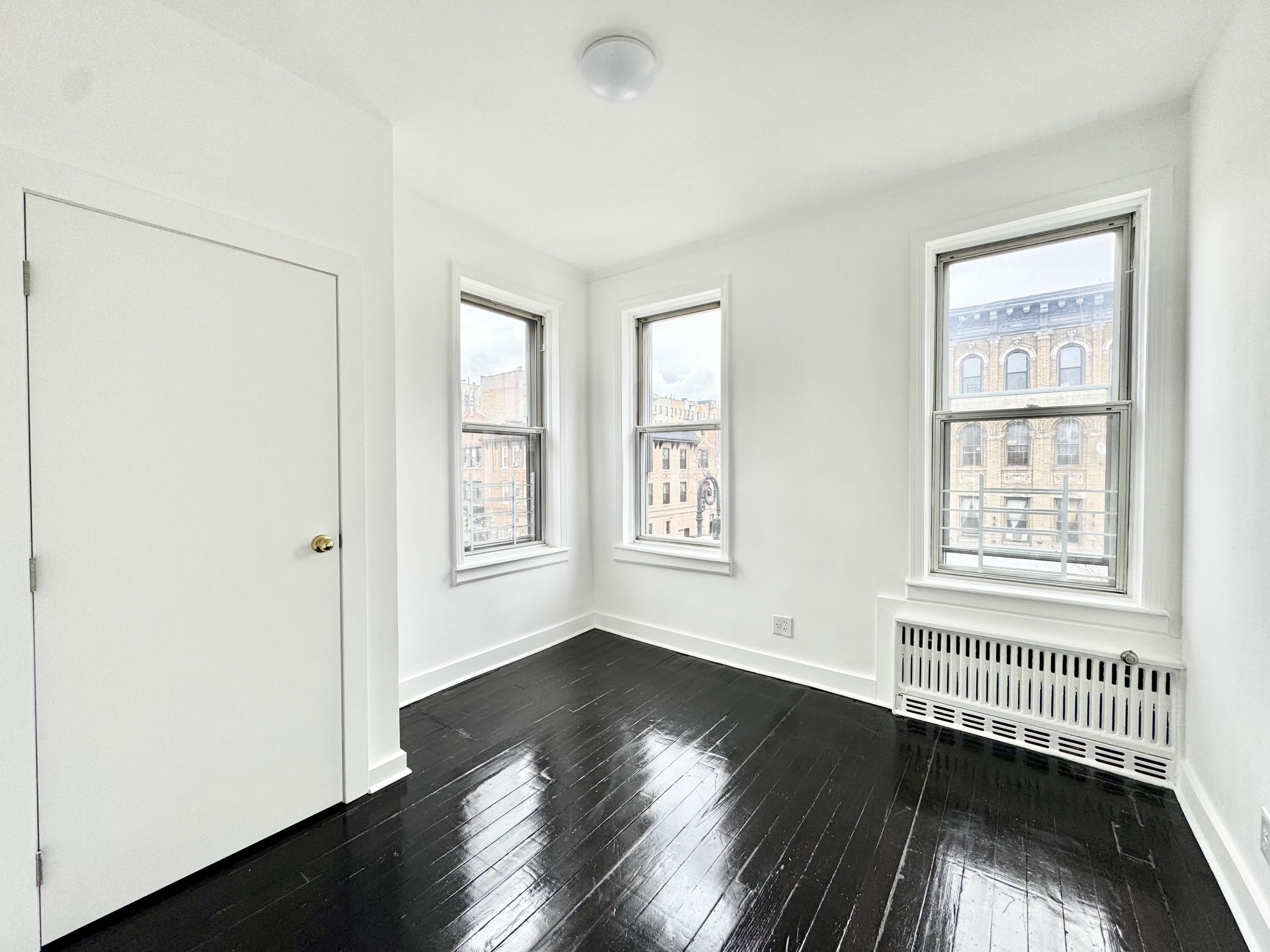 406 Rogers Avenue, Unit 3 Brooklyn, NY 11225 - Photo 5 of 9 a view of an empty room with wooden floor and a window