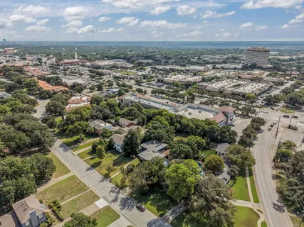an aerial view of a residential houses with outdoor space and trees