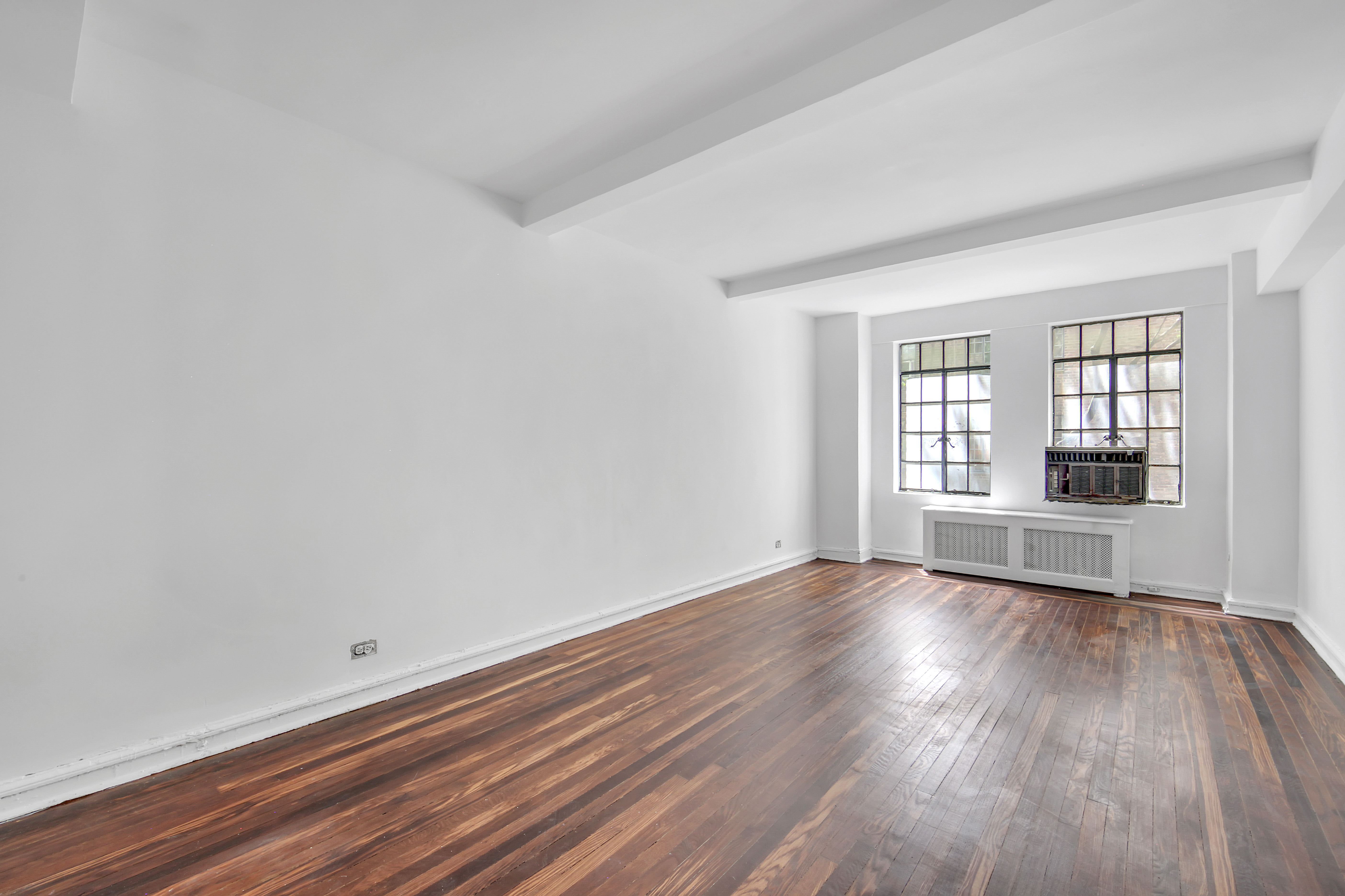 320 East 42nd Street, Unit 516 Manhattan, NY 10017 - Photo 3 of 11 an empty room with wooden floor and windows