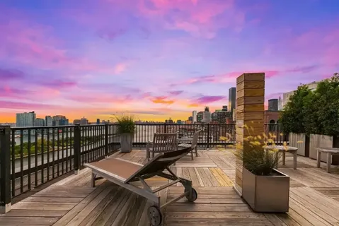 a view of a rooftop deck with chairs and wooden floor