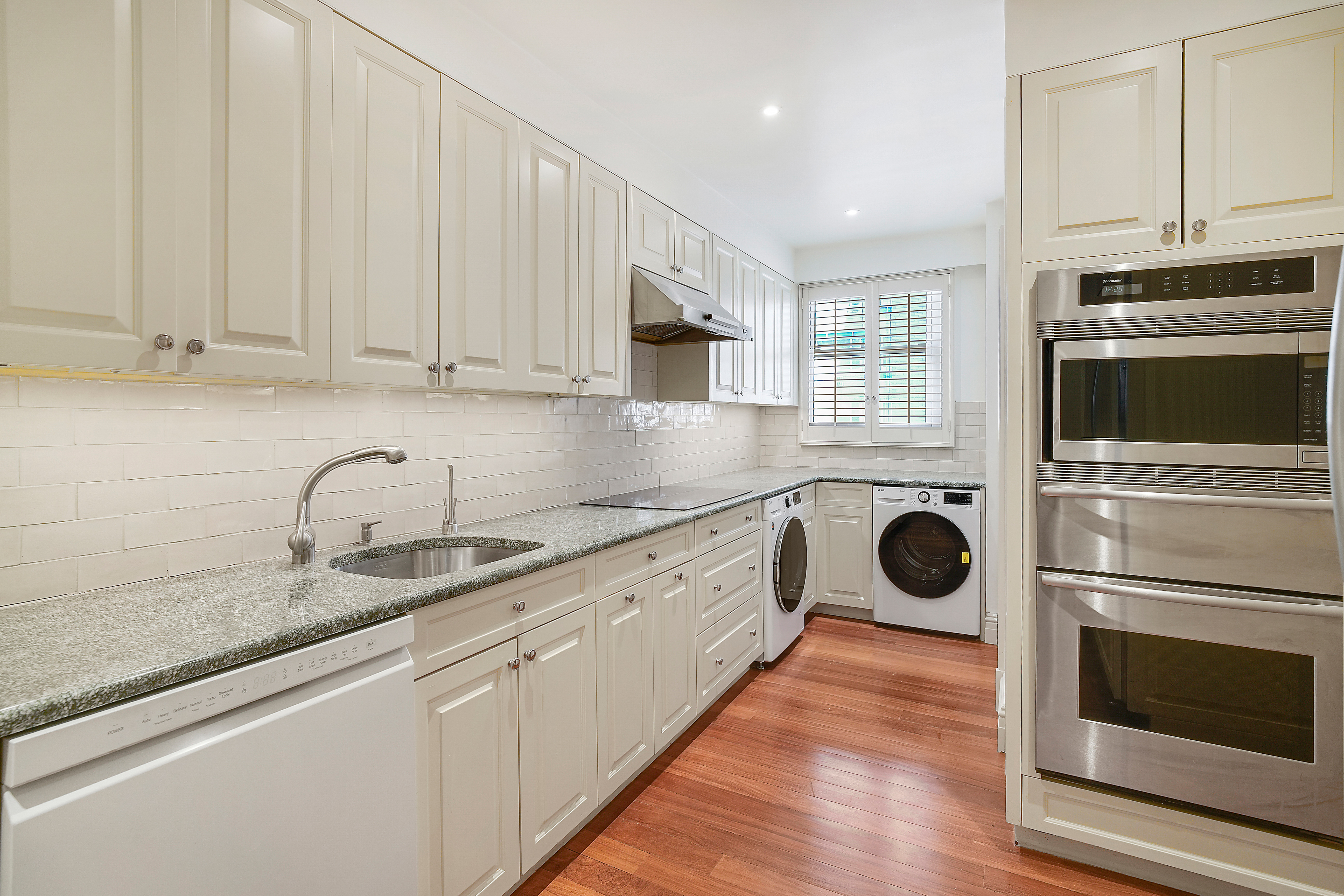 175 East 62nd Street, Unit 8D Manhattan, NY 10065 - Photo 11 of 24 a kitchen with granite countertop stainless steel appliances a stove microwave and sink