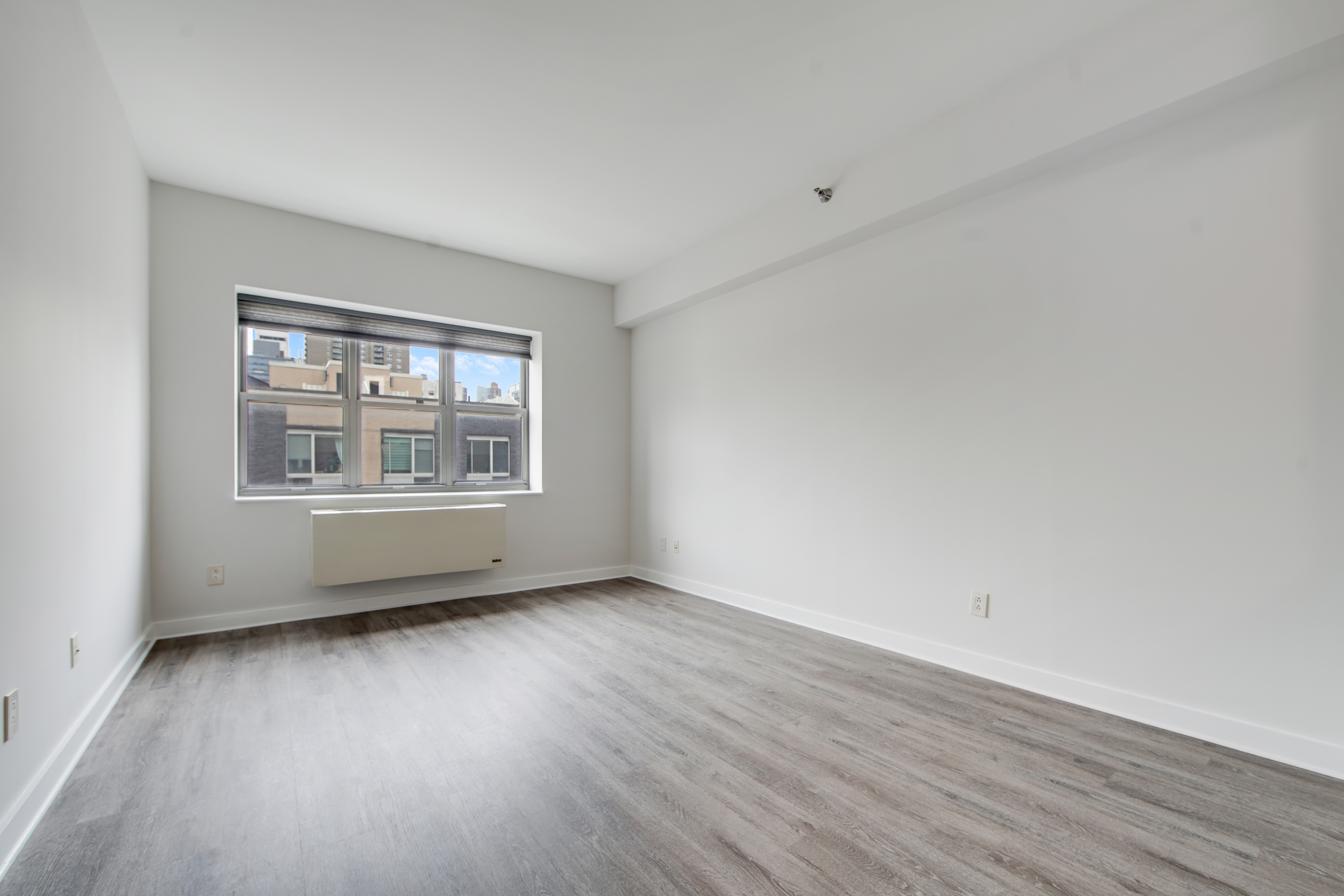 516 West 47th Street, Unit N7A Manhattan, NY 10036 - Photo 2 of 19 a view of an empty room with wooden floor and a window