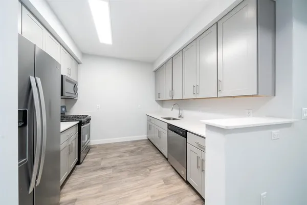 a kitchen with stainless steel appliances granite countertop a refrigerator a stove and a sink