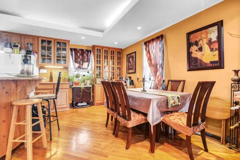 a view of a dining room with furniture one side kitchen view and wooden floor